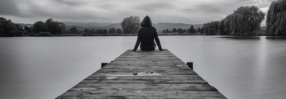 photo of a man sitting at the end of a dock, contemplating a divorce from his spouse with the help of Capital City Law Edmonton Family Lawyers